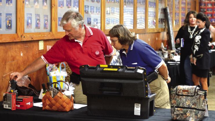 David (left) and Debra Peters inspect silent auction items on display at the Lampasas County Livestock Association’s Reverse Raffle fundraiser on Saturday. ERICK MITCHELL | DISPATCH RECORD