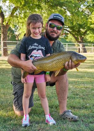 Teagan Eicher, 5, poses with the 27-inch fish she caught during KidFish on Friday evening. She is pictured here with her father, Derrick Eicher. ADAM BARRIOS | DISPATCH RECORD