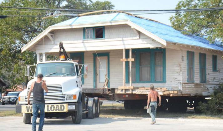 King House Moving crew member Rodney Henshaw, in black shirt, gives guidance on Friday as company owner John King transports a house from 105 W. First St. to the house’s new location, 374 Supple Dr. Also pictured is crew member Shane Paduch. DAVID LOWE | DISPATCH RECORD