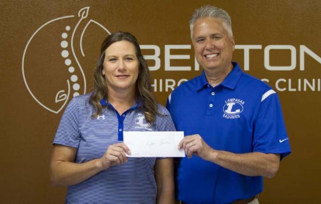 Jan Brister receives a check from Craig Benton for $500 that will go toward improvements for the athletic training department. HUNTER KING | DISPATCH RECORD