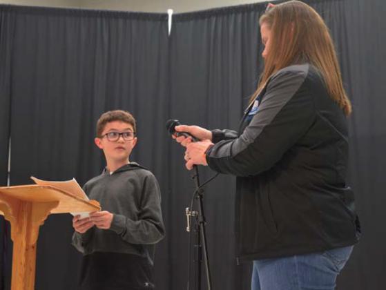 Jace Walkowiak receives the microphone from Taylor Creek counselor Carisa Brown before reading his poem aloud. erick mitchell | dispatch record