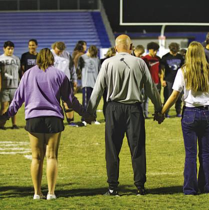 Students from Lampasas and Lometa gather on Badger Field to pray at the conclusion of the Fields of Faith event Wednesday night. The local chapter of Fellowship of Christian Athletes hosts the annual night of student-led prayer and fellowship. HUNTER KING | DISPATCH RECORD