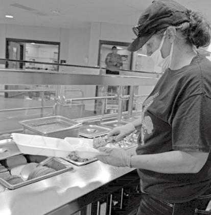 Brigitte Adler-Brown, high school cafeteria manager, assembles a to-go meal. Students no longer are allowed to customize their plates but instead receive pre-packaged meals. MADELEINE MILLER | DISPATCH RECORD