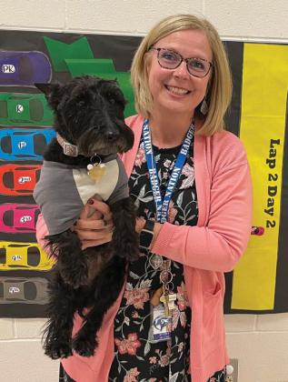 Taylor Creek Principal Shona Moore holds school dog Nessy as she stands in front of a paper racetrack. Every class at each grade level has a car on the track. Classes that have perfect attendance move to the finish line to obtain a Coke float as a reward. erick mitchell | dispatch record