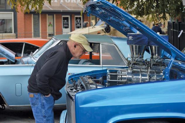 ERICK MITCHELL | DISPATCH RECORD Carl French looks underneath the hood of an antique truck on display Saturday at the Classics at the Classic car show on the downtown square.