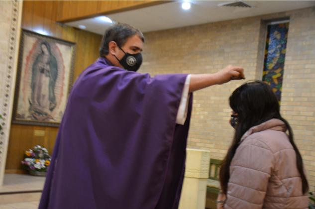 The Rev. Paul Hudson, priest of St. Mary Catholic Church in Lampasas, sprinkles ashes on Jessenia Villegas’ head during an Ash Wednesday evening Mass. The imposition of ashes this year was by sprinkling – rather than imprinting on the forehead – because of COVID-19 precautions. DAVID LOWE | DISPATCH RECORD