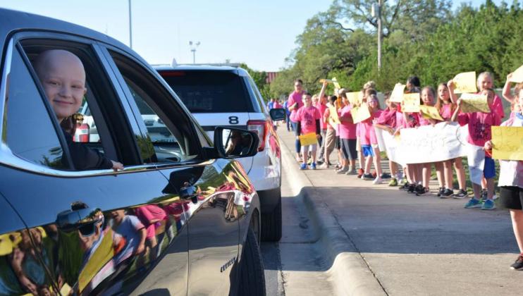 Hanna Springs Elementary School first-grader CJ Cluck, left, is cheered on by his classmates during a drive-by event at the school. He hasn’t seen his teachers or classmates since February, as the student is battling Ewing sarcoma, a rare form of cancer. MONIQUE BRAND | DISPATCH RECORD
