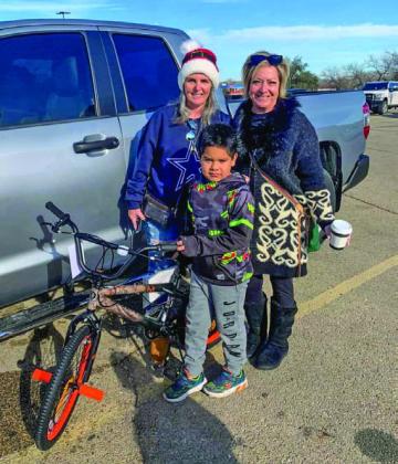 David Flores, center, poses for a photo with his new bicycle, a gift from Vicki Taylor and Wendi Boylan Wulstein, left to right. COURTESY PHOTO