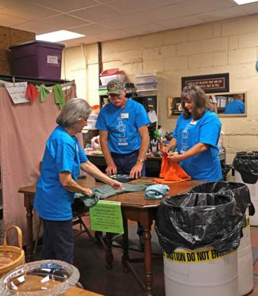 joycesarah mccabe | dispatch record Billy James and Marilyn James stand on one side of the clothing sorting table folding T-shirts, while Frieda Gayheart stands on the other side and assists.