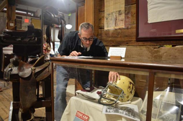 Museum board member John Fingerhut props up a Texas A&amp;M football helmet at the Lampasas County Museum on Friday morning. The exhibit opens to the public this week. MONIQUE BRAND | DISPATCH RECORD