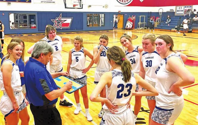 Head coach Mark Myers speaks to his team in the huddle while they are up late in a tournament game, and a few girls strike a pose for the camera. COURTESY PHOTO