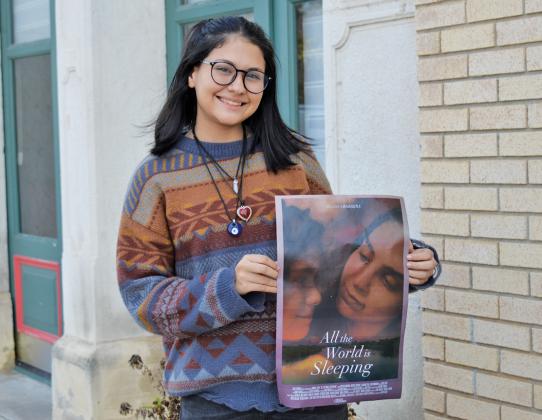 Adilynn Menendez holds a poster from the newly released film “All the World is Sleeping,” in which she earned her first movie role. erick mitchell | dispatch record