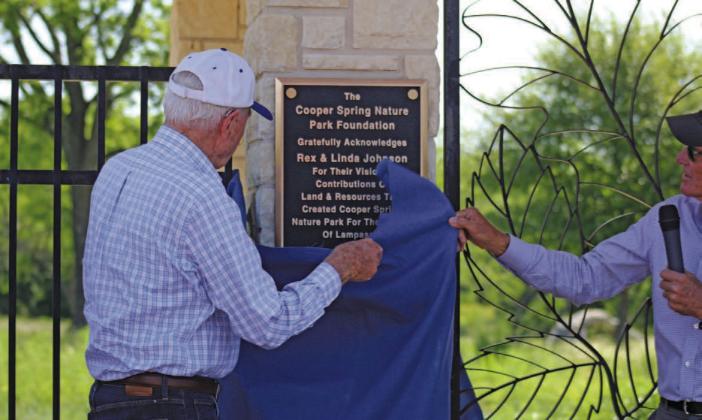 Rex Johnson, assisted by Harrell Clary at right, unveils the plaque dedicating Cooper Spring Nature Park and recognizing Johnson and his wife, the late Linda Johnson, for their work and generosity in making the park a reality. JOYCESARAH MCCABE | DISPATCH RECORD