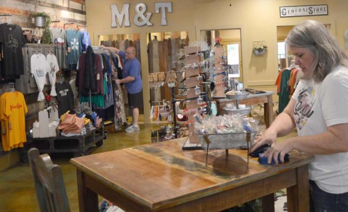 Jo Williams, foreground, and John Williams stock merchandise in the Merk &amp; Tilley’s boutique on the downtown square. Since May, when COVID-19 restrictions eased and the business was allowed to reopen, Merk &amp; Tilley’s revenue has grown by at least 25% each month, John Williams said. FILE PHOTO