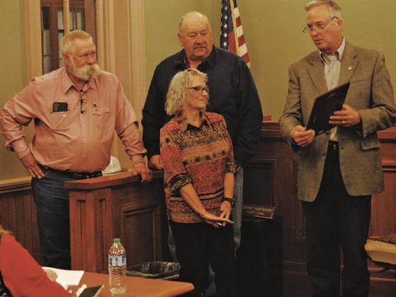 The Lampasas County Commissioners Court presented retiring County Clerk Connie Hartmann with a plaque to recognize her service over the last four decades. Standing behind Hartmann are Precinct 3 Commissioner Lewis Bridges, at left, and Precinct 4 Mark Rainwater as County Judge Randy Hoyer, at right, reads from Hartmann’s plaque. HUNTER KING | DISPATCH RECORD