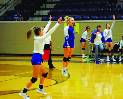 Kayli Syx, left, and Bre Quarles celebrate a point during the playoff matchup. Head coach Christy Wiley and the bench also show their excitement. HUNTER KING | DISPATCH RECORD