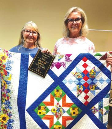 Best of Show winner Naomi Schroyer, at left, displays her winning quilt entry, with assistance from Cathy Allen of the ‘36 Club. MASON HINES | DISPATCH RECORD