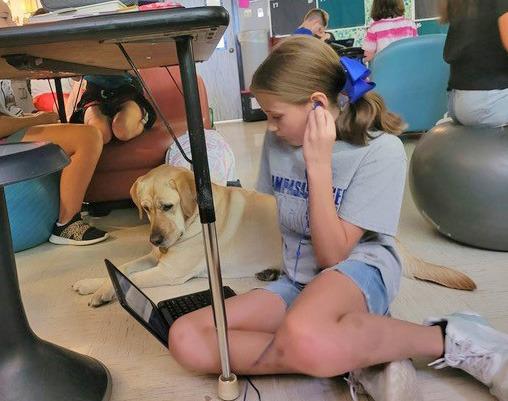 courtesy photo Honey, the Kline Whitis Elementary campus dog, sits with fifth-grader Ava Preece as she does her work.