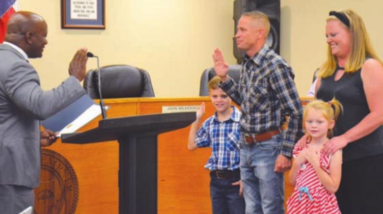 Mayor Dr. Keith Harvey, left, administers the oath of office on Tuesday to new Place II City Councilman Jared Jones. With Jones are his wife, Ashley; his daughter, Victoria; and his son, Jackson. DAVID LOWE | DISPATCH RECORD