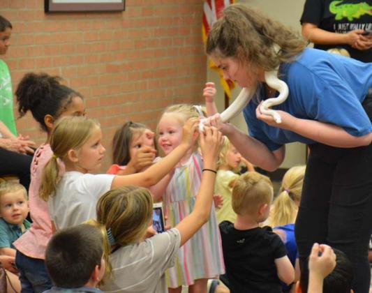 Lotus Blewett holds the Humane group’s leucistic snake as young library patrons have a chance to feel its scales. MASON HINES | DISPATCH RECORD