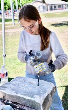 After watching several boys try their hand at carving stone, 11-year-old Hadley Steele decided she could do it, too. “It was really kind of fun,” she said after carving an “H” into the stone surface. joycesarah mccabe | dispatch record