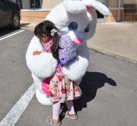 Two-year-old Lampasan Zaria Eva Ashley Rivera hugs the Easter Bunny tightly during the Aware Central Texas Easter kit drivethrough at the Lampasas Police Department headquarters. MONIQUE BRAND | DISPATCH RECORD