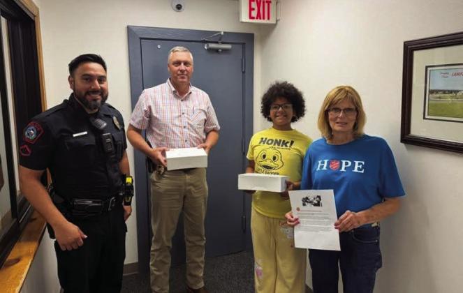 Dorothy Person, at right, and her granddaughter Nikita Olson deliver doughnuts to the Lampasas Police Department, where School Resource Officer John Resa and Assistant Chief Charlie Boswell accepted the treats for the department to share. COURTESY PHOTO