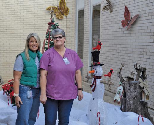 Erick mitchell | dispatch record Kline Whitis Elementary School Principal Leanne Bobo, at left, and custodian Mary Ejem stand In the life-size snow globe creation Ejem designed at the campus.