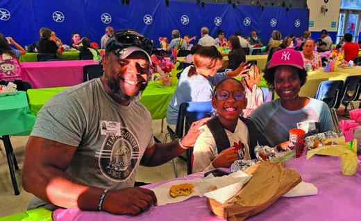At center, Vira Davis sheds a smile as she enjoys a meal with her parents Patrick, at left, and Angela. COURTESY PHOTO