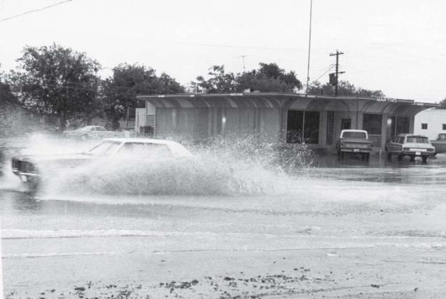 A car passes through the flooded roadway at Key Avenue and Seventh Street. A low-water crossing was created across Key Avenue at this intersection in the 1950s to channel runoff from the west side of the roadway. lampasas dispatch record, April 1971