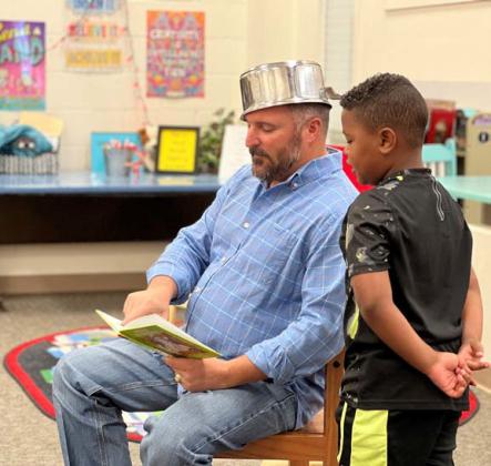 Lampasas ISD school board member Jeff Rutland, decked out as Johnny Appleseed, reads a book alongside first-grader Eli Vazquez on Monday. court esy photo