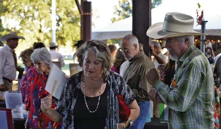 Delaine Shroyer (left) and husband Ronny Shroyer look for the perfect silent auction item during Saturday’s Boots and Blazers Ball hosted by the Lampasas Association for the Arts. ERICK MITCHELL | DISPATCH RECORD