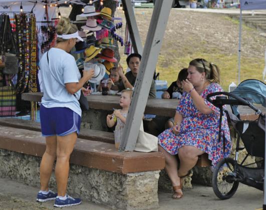 Lampasas residents Amy Vann, at left, and Leyna Brewer and her daughter enjoy concessions and shopping among the park vendors while out for Spring Ho festivities. ERICK MITCHELL | DISPATCH RECORD