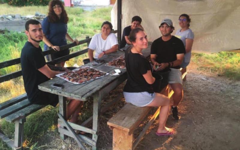 Wright, second from right, cleans recently excavated pottery with Romanian collaborators. Each evening, excavation team members document their findings, which provide information about the age and culture of ancient settlements. COURTESY PHOTO