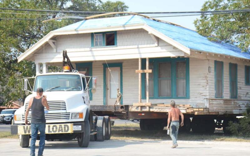 King House Moving crew member Rodney Henshaw, in black shirt, gives guidance on Friday as company owner John King transports a house from 105 W. First St. to the house’s new location, 374 Supple Dr. Also pictured is crew member Shane Paduch. DAVID LOWE | DISPATCH RECORD