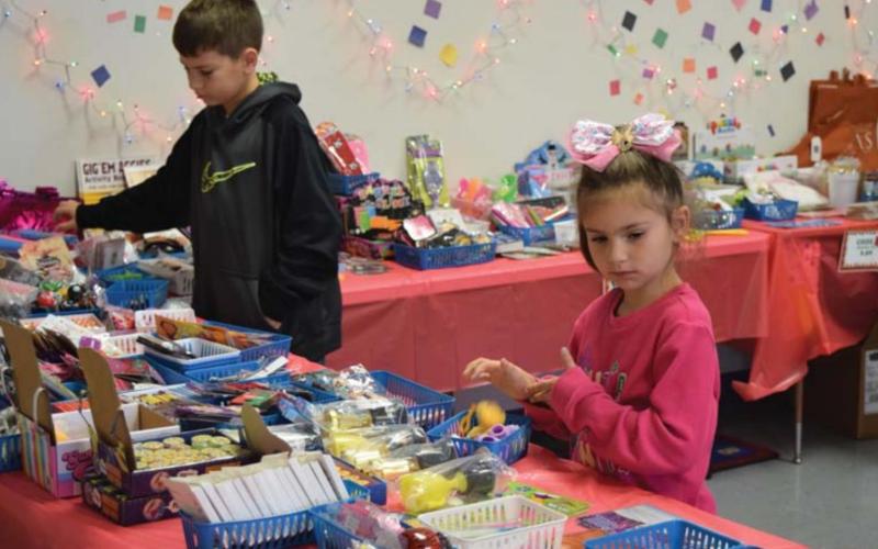 Fourth-grader Brenton Withers and first-grader Mya Rodriguez shop at the Peppermint Village Gift Shop at Hanna Springs Elementary on Tuesday. ALEXANDRIA RANDOLPH | DISPATCH RECORD