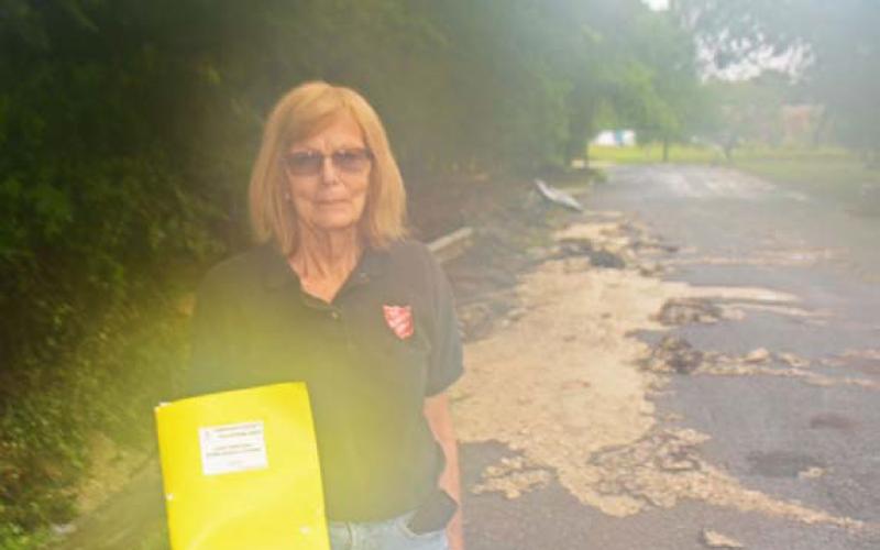 Dorothy Person, a local Salvation Army volunteer, pauses for a photo in front of the flood damages on Avenue H last month. COURTESY PHOTO