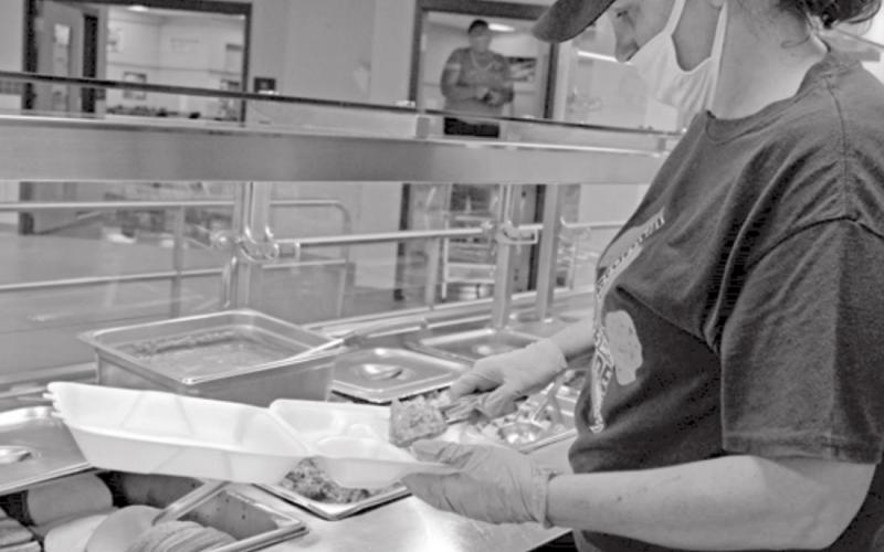 Brigitte Adler-Brown, high school cafeteria manager, assembles a to-go meal. Students no longer are allowed to customize their plates but instead receive pre-packaged meals. MADELEINE MILLER | DISPATCH RECORD