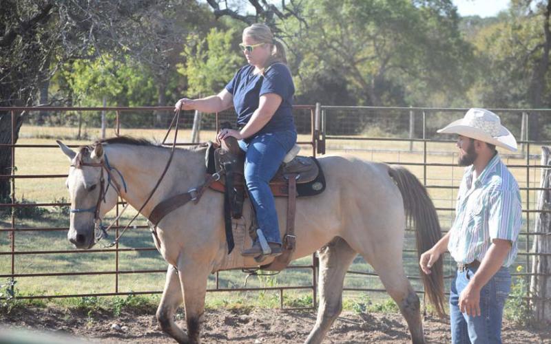 U.S. Armed Forces veteran Krystal Ybarra, a Camp Cowboy program participant, rides “CD” around an arena under the supervision of Lane Robison, program director. Alexandria Randolph | dispatch record