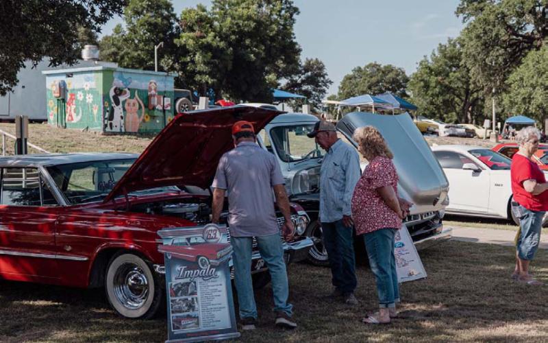 Residents check out the engine of one of the exhibitors at the Sulphur Creek Car Cruise. ADAM BARRIOS | DISPATCH RECORD