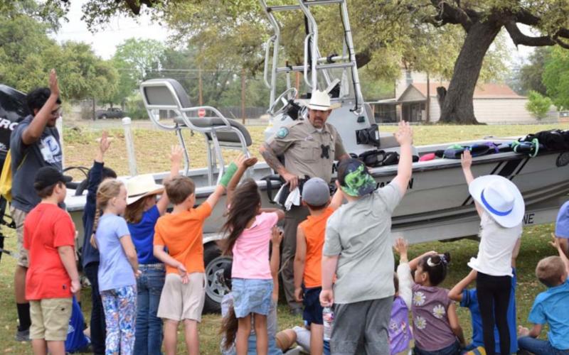 Lampasas County Game Warden Ray Milloway prepares to demonstrate proper and ill-fitting life preservers with the help of some volunteers from Victor Becerra’s first-grade class. ALEXANDRIA RANDOLPH | DISPATCH RECORD