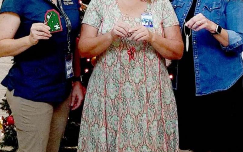 Lampasas High School staff members, from left, Tracey Davis, Shelly Myers and Traci Shaughnessy stand in front of the Angel Tree, holding ornaments that describe a child’s Christmas wish list. COURTESY PHOTO
