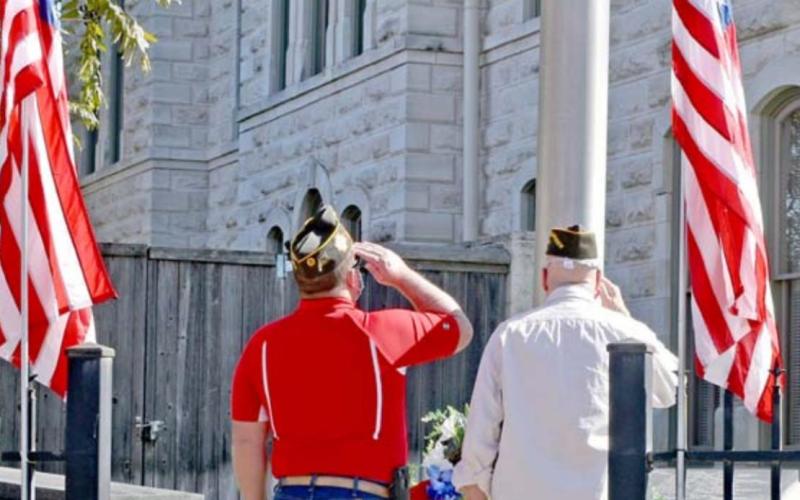Keith Callis, left, and Jackie Keys salute a wreath after laying it at the base of the courthouse flagpole to honor those who died while serving in the armed forces. MADELEINE MILLER | DISPATCH RECORD