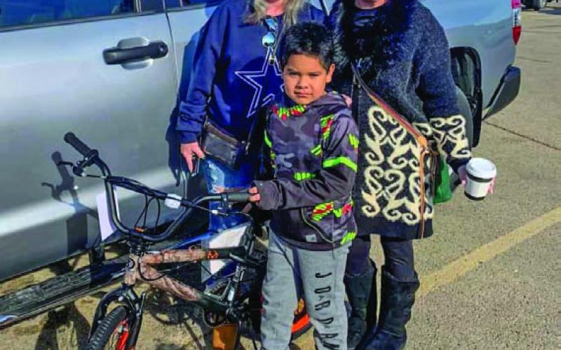 David Flores, center, poses for a photo with his new bicycle, a gift from Vicki Taylor and Wendi Boylan Wulstein, left to right. COURTESY PHOTO