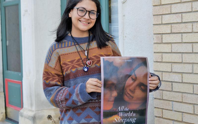 Adilynn Menendez holds a poster from the newly released film “All the World is Sleeping,” in which she earned her first movie role. erick mitchell | dispatch record