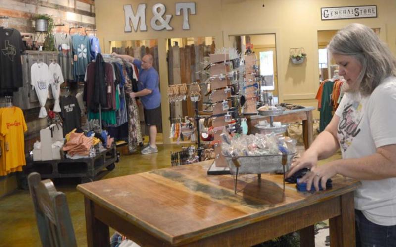 Jo Williams, foreground, and John Williams stock merchandise in the Merk &amp;amp; Tilley’s boutique on the downtown square. Since May, when COVID-19 restrictions eased and the business was allowed to reopen, Merk &amp;amp; Tilley’s revenue has grown by at least 25% each month, John Williams said. FILE PHOTO
