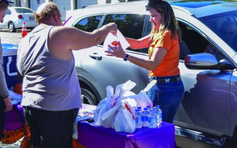 Volunteers help distribute barbecue sandwiches curbside at a previous BBQ for Books event. FILE PHOTO
