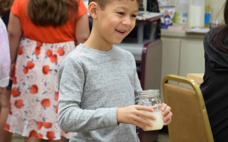 William Alexander, 7, brings a mixture of milk and lemon juice back to his table, where he will shake it until it curdles and becomes butter as part of an emulsion process. Solutions and colloids were the focus of a youth chemistry event held Tuesday at the Lampasas Public Library. ALEXANDRIA RANDOLPH | DISPATCH RECORD