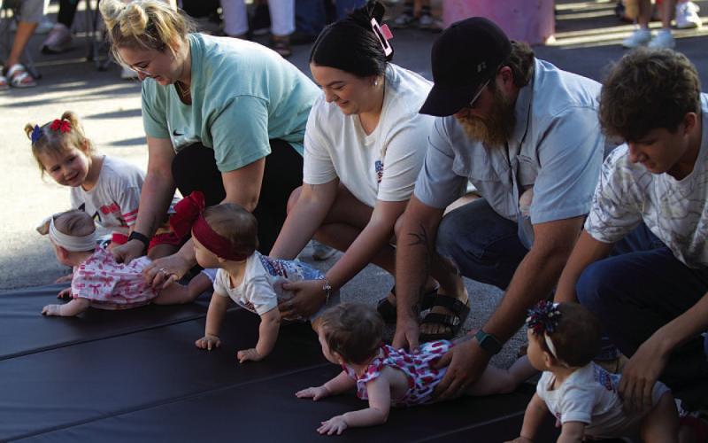 Parents help line up their baby racers before Diaper Derby action gets underway outside the Lampasas County Courthouse on Friday morning. HUNTER KING | DISPATCH RECORD