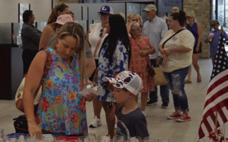ERICK MITCHELL | DISPATCH RECORD Before visiting shops along the square, attendees received their glasses and punch cards for raffle prizes at First Texas Bank.